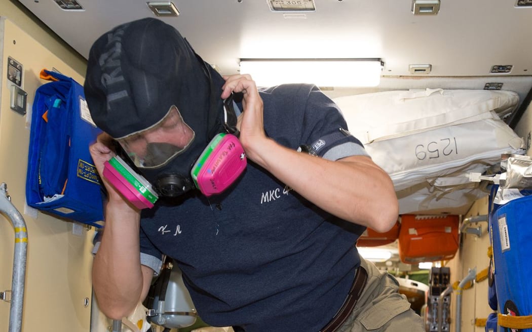 NASA astronaut Kjell Lindgren wears protective breathing apparatus that would be used in the unlikely event of a fire or hazardous chemical leak inside the pressurized air volume of the International Space Station.
