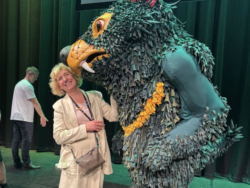 A woman stands with a person in a costume.