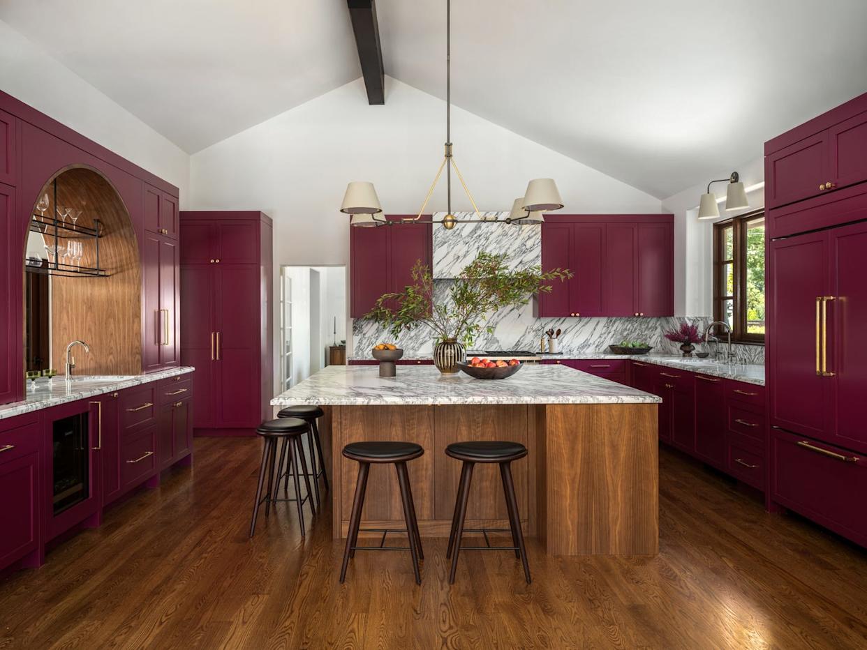 Modern kitchen featuring burgundy cabinetry and marble countertops.