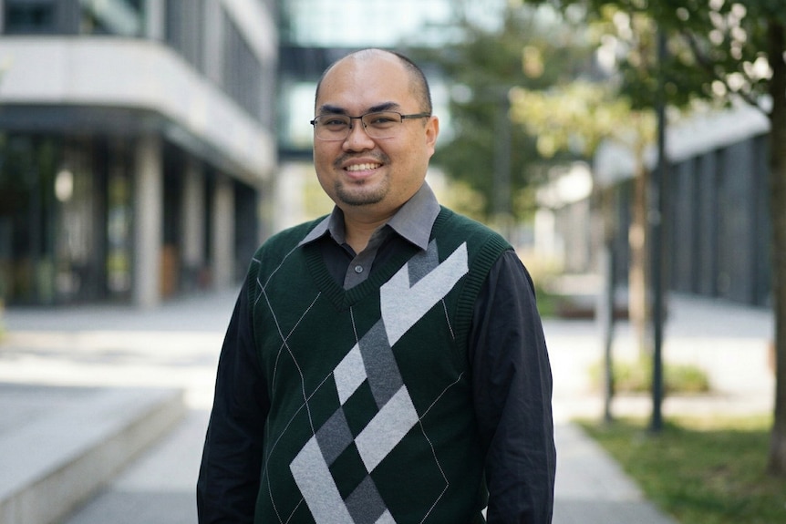 A man wearing glasses smiling to camera.