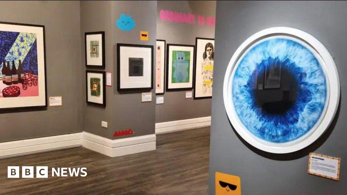 A gallery space with grey walls that has colourful artworks hanging on the walls.