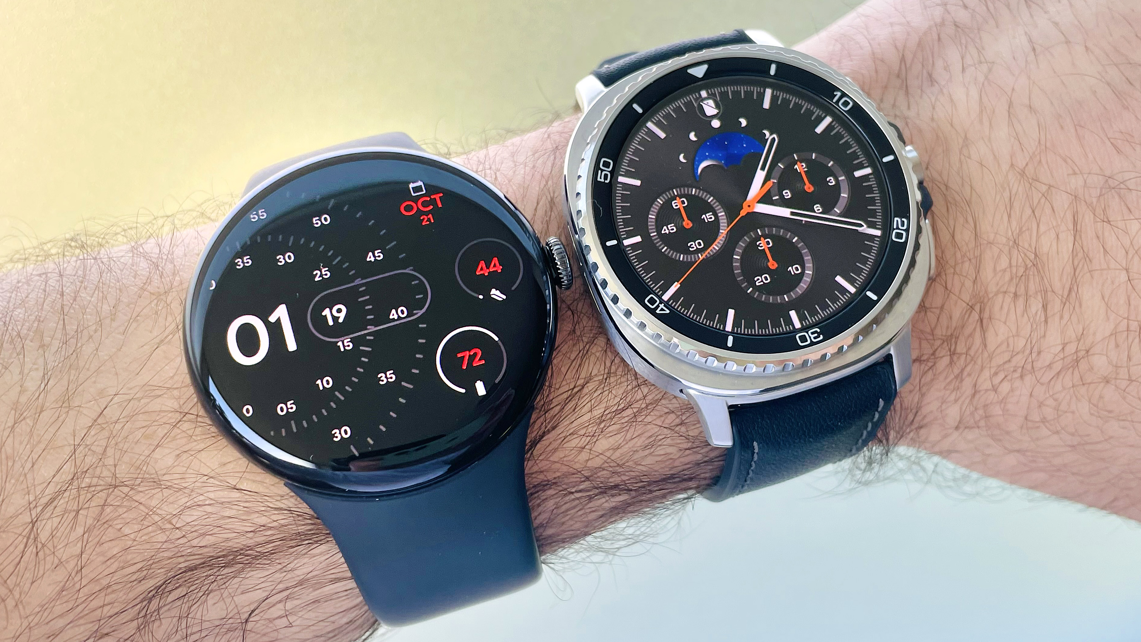 Close-up of the Google Pixel Watch 4 on a user's wrist next to the Samsung Galaxy Watch 8 Classic