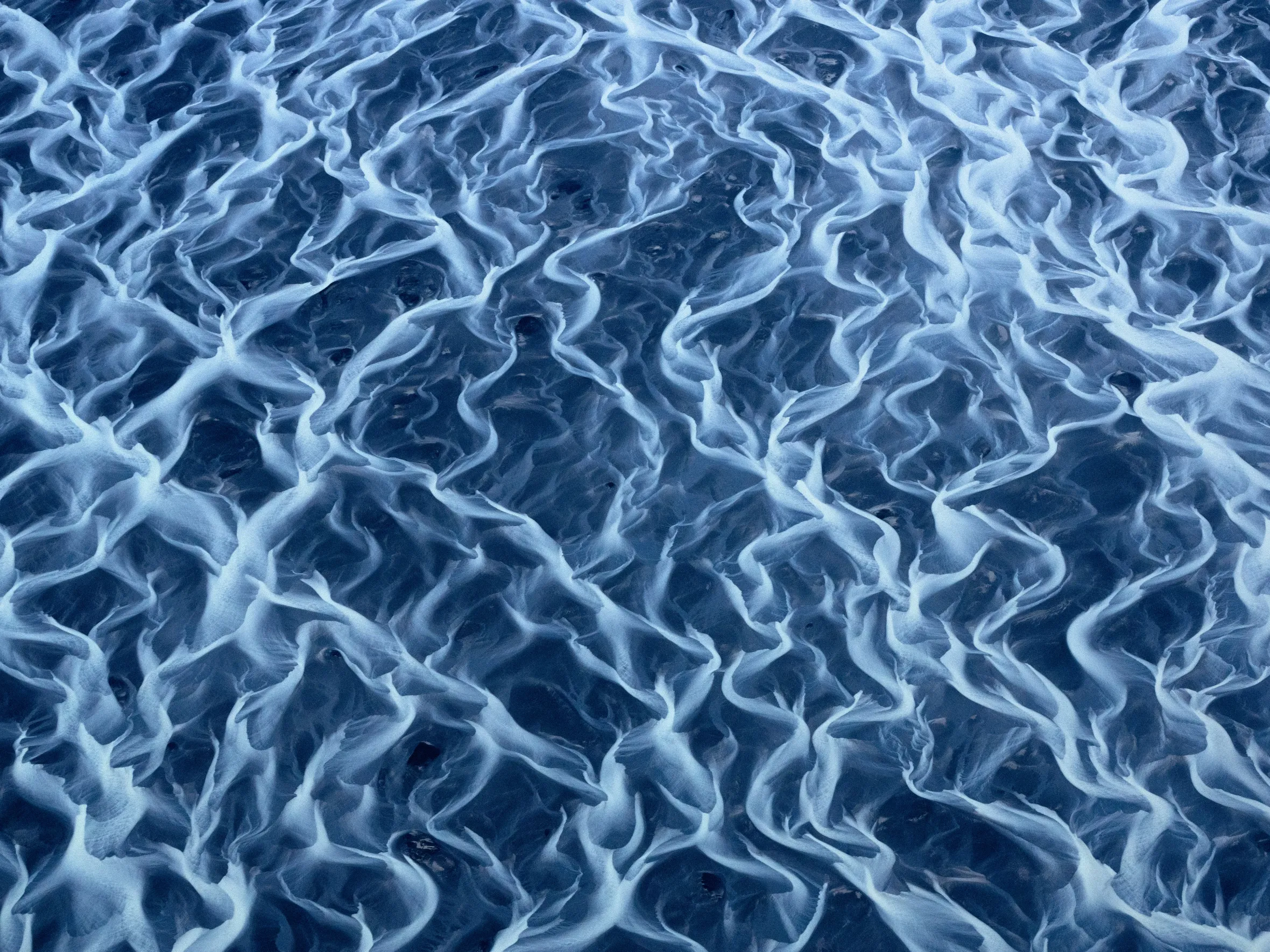 Braided rivers in Iceland with glacial water winding through volcanic sand.