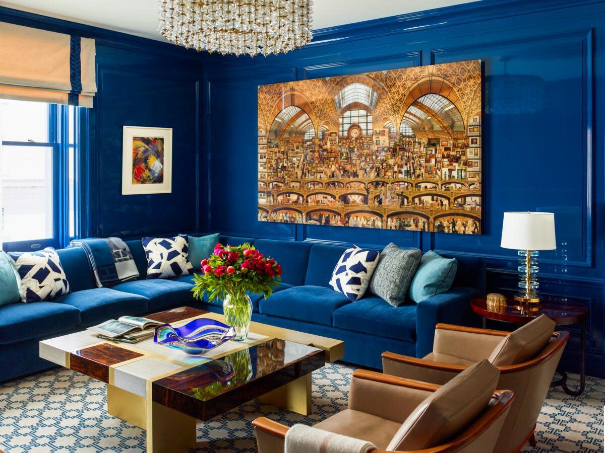 Modern living room with blue walls, artwork, and elegant furniture.