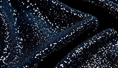 An extreme close-up photograph of a shimmering, glittering fabric texture in dramatic studio lighting, conveying a sense of luxury and glamour associated with the entertainment industry.