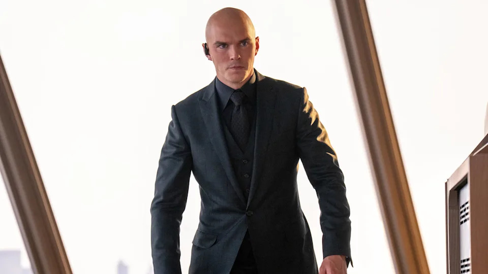 Nicholas Hoult's Lex Luthor dressed in black suit standing near a large window behind him