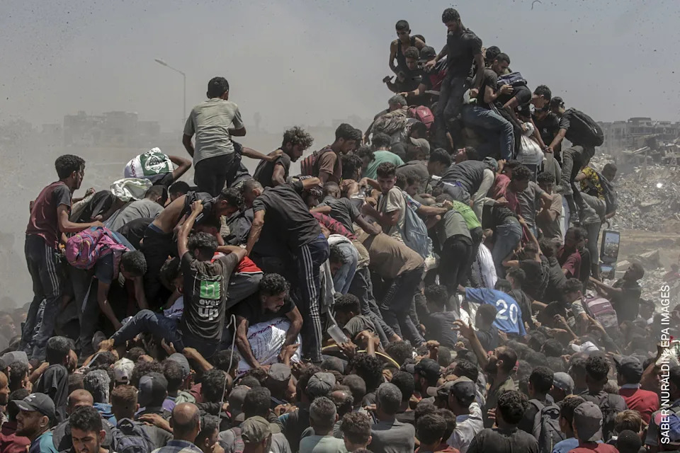 Palestinians climb onto an aid truck as it enters the Gaza Strip via the Zikim Crossing in an attempt to get flour, during what the Israeli military called a “tactical suspension” in operations