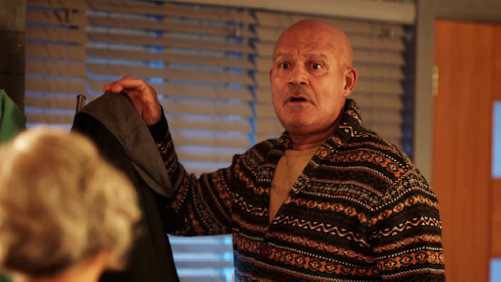 a man holding a piece of clothing in a room with blinds