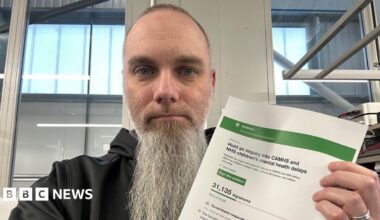 Tom is holding a petition in his hands and wearing a black hoodie.