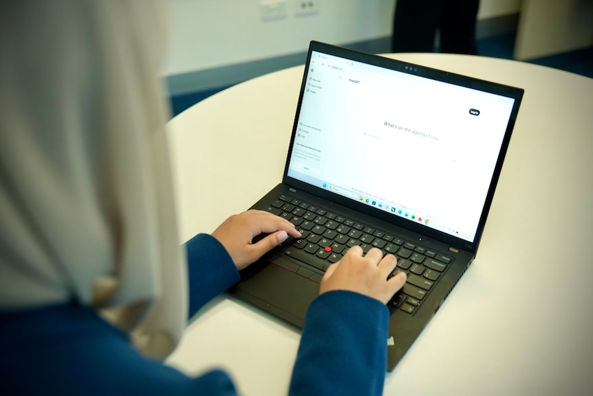 Hands type on a laptop keyboard, with the screen displaying the chatgpt website.