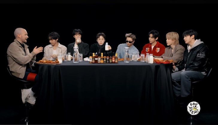 Members of BTS sit with host Sean Evans, left, during their appearance on YouTube talk show “Hot Ones,” taking on progressively spicier wings while answering questions. Captured from First We Feast YouTube Channel