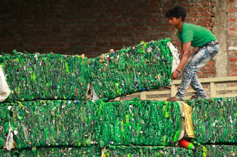 A worker loads bundles of PET plastic bottles onto a truck for recycling at an industrial area on the outskirts of Jammu in 2018. Experts say even PET, considered the best recyclable plastic, can only be recycled a few times. (AP Photo/Channi Anand)