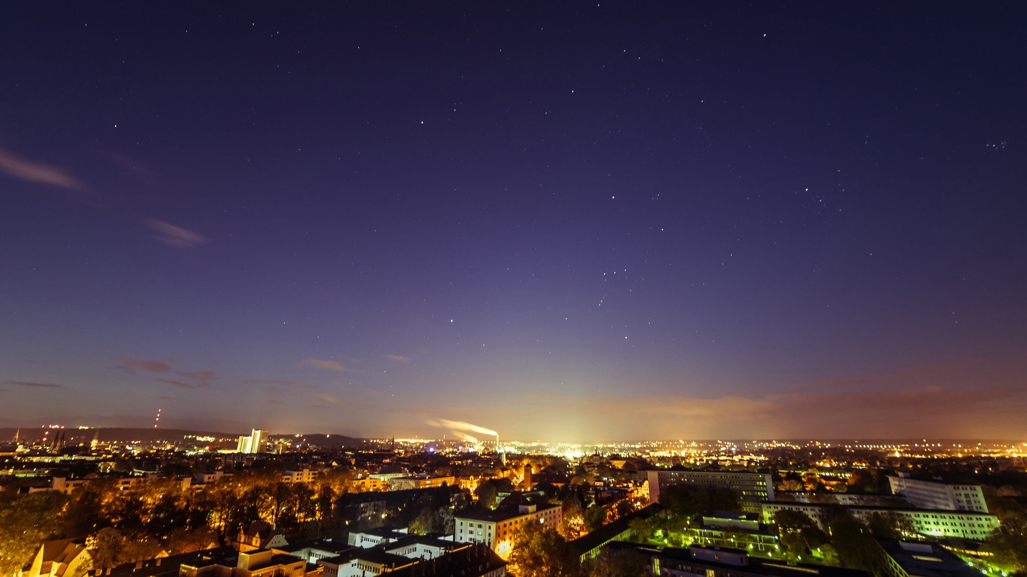 a city scape at night with stars shining in the sky above.