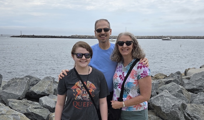 Three white people, two parents and their 20-something daughter, standing outside