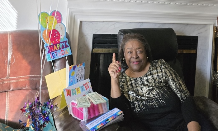 A black woman posing with birthday gifts and knick knacks