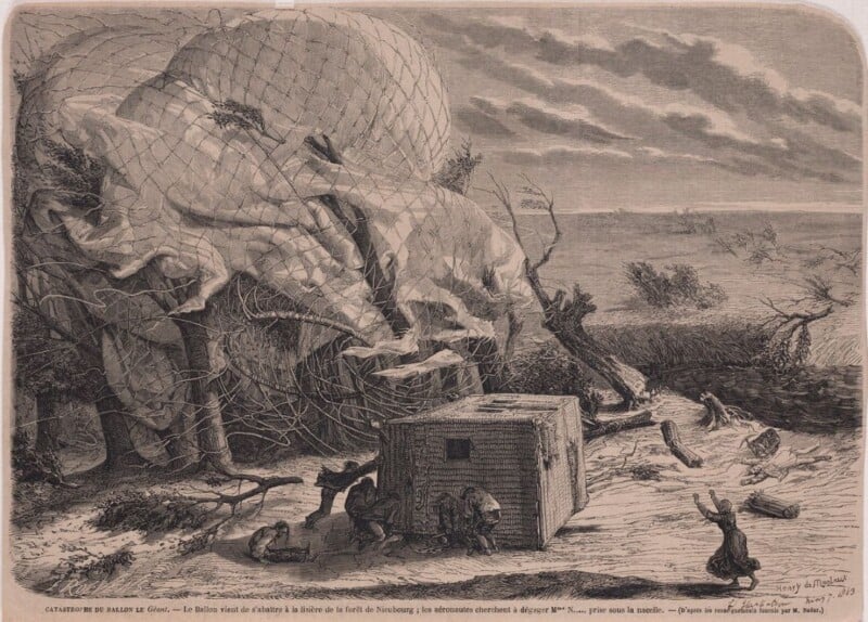 A large collapsed hot air balloon lies tangled in trees in a forest clearing. Several people inspect the scene, with a basket on the ground and broken branches scattered around. The sky is cloudy and the landscape appears windy.
