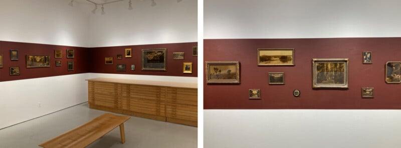 Two side-by-side photos show a gallery corner with a maroon accent wall displaying variously sized, framed landscape paintings and photographs above wooden cabinetry and a wooden bench.