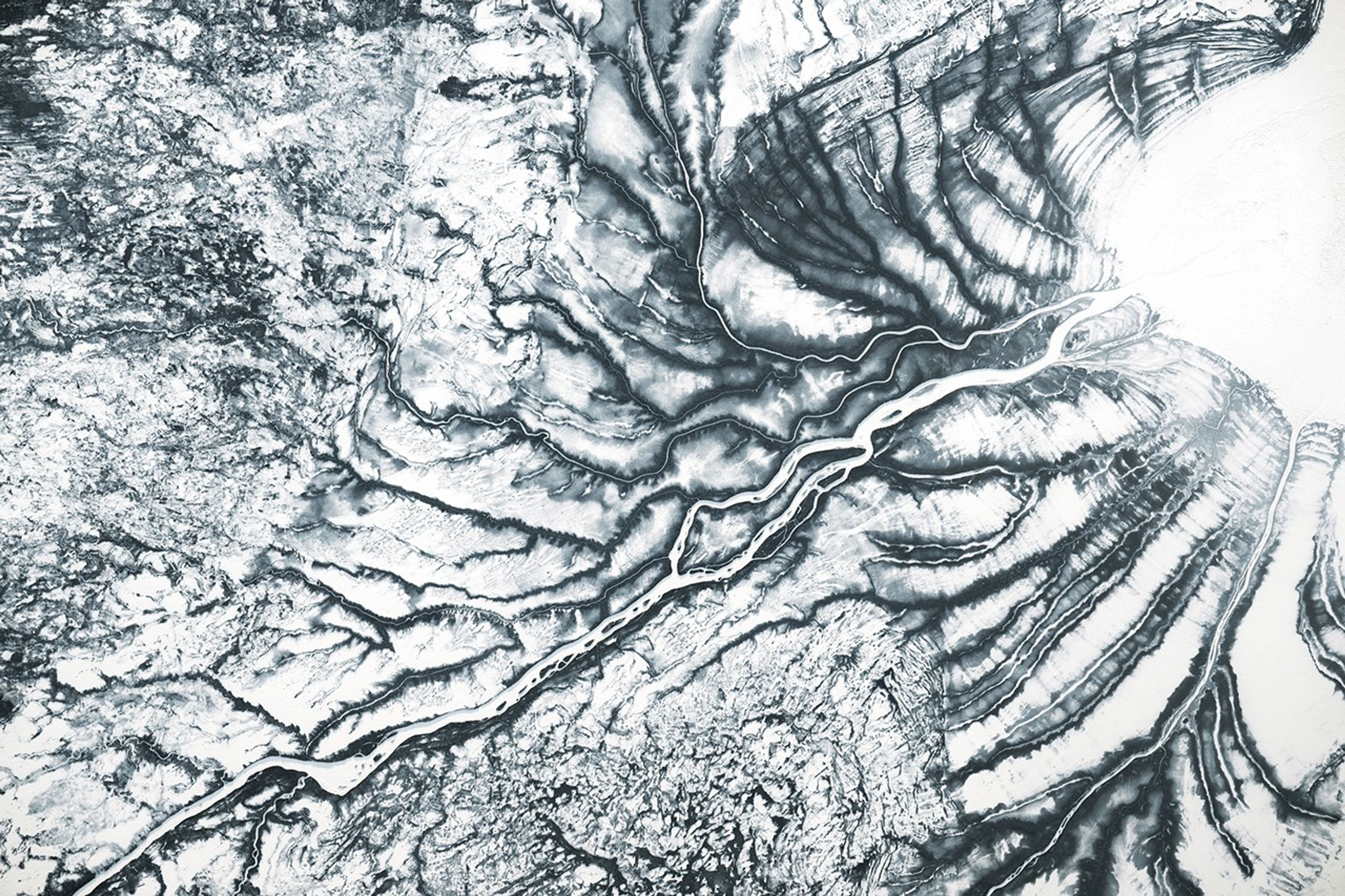 A snowy landscape in northern Canada reveals frozen river channels as well as ridges parallel to the shore of an icy bay in the upper right.