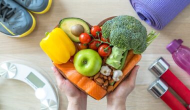 Heart shaped plate filled with vegetables. Background shows running trainers, small dumbbells and scales for heart health and nutrition concept