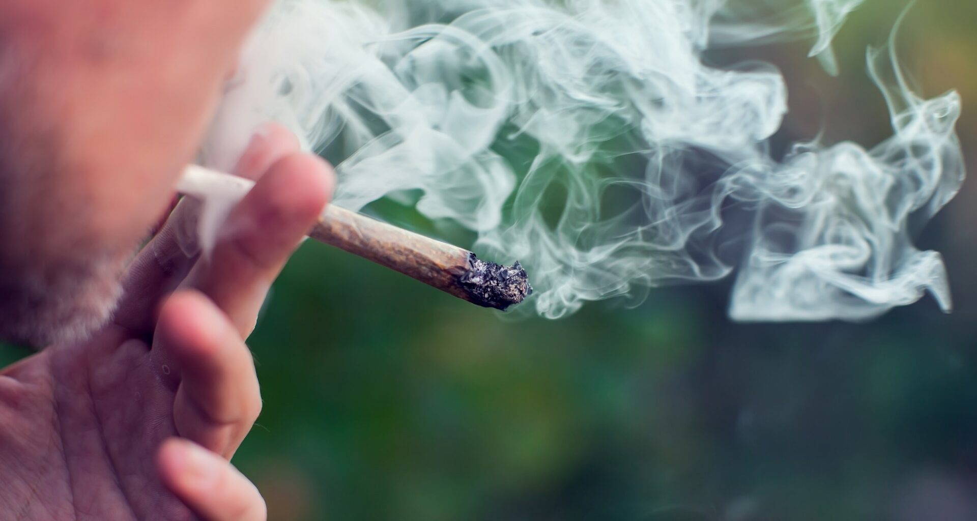 Young man smokes a joint of cannabis