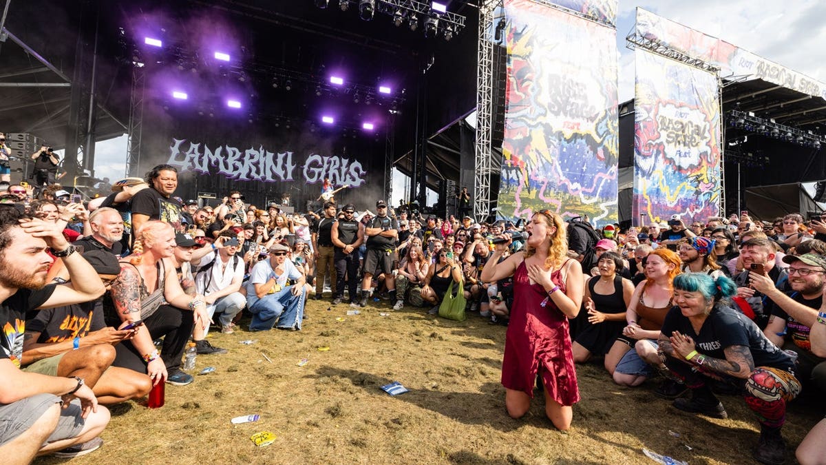 Phoebe Lunny of Lambrini Girls performing onstage in front of a crowd.