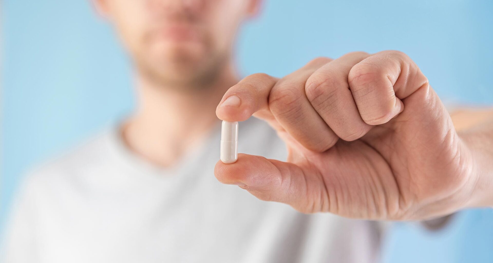 Man Holding White Capsule Supplement Pill