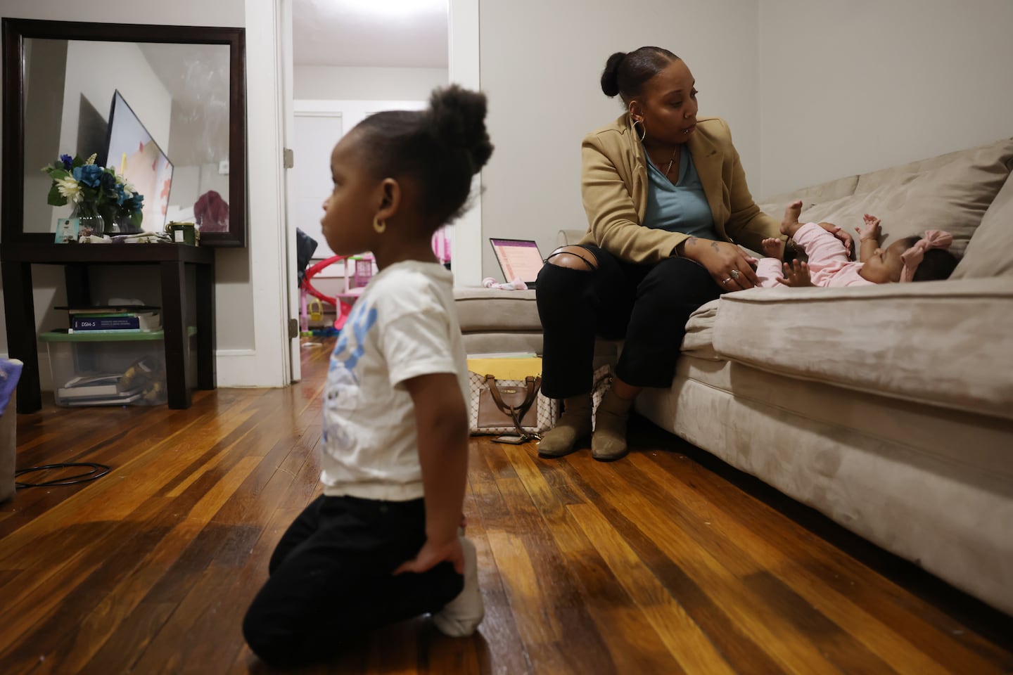 Brianna Smith-Thomson, a 35-year-old mother of three, played with her 5-month-old daughter, Serenity, on the couch as her other daughter, Heavyn, 4, watched television in the family’s living room in Lynn.