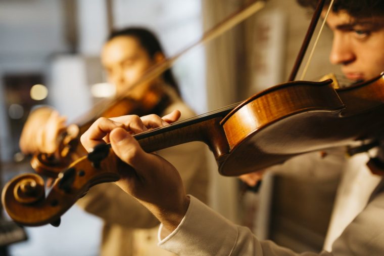 Two young musicians playing a violin in a rehearsal