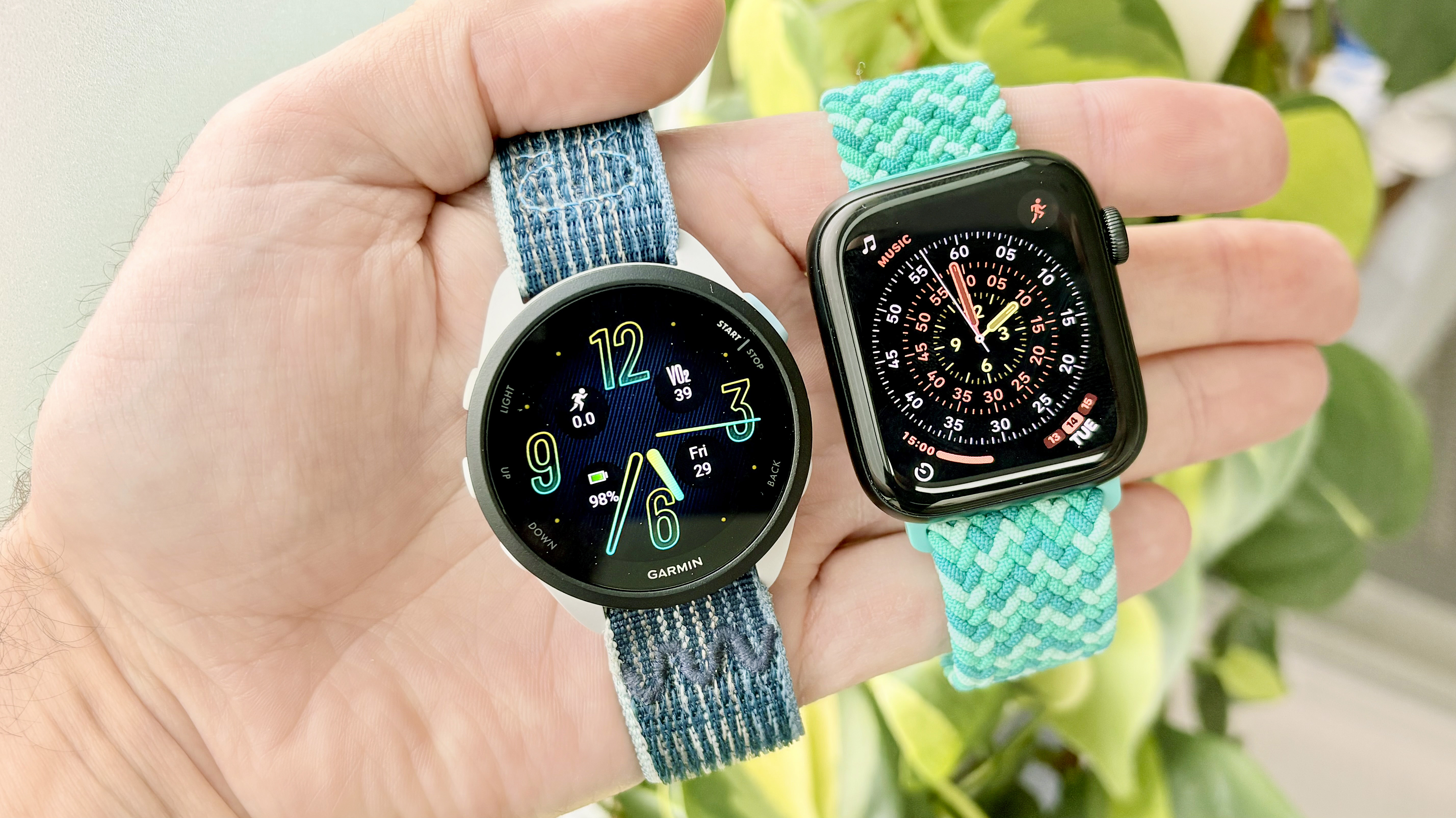 Close-up of the Garmin Forerunner 165 next to the Apple Watch SE 3