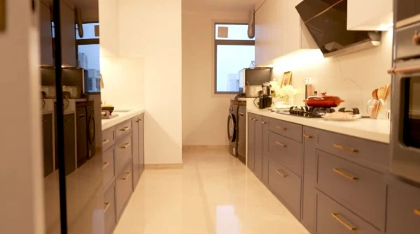 The kitchen prioritises functionality without compromising on style. Designed in a sleek parallel layout, it features grey cabinetry paired with a crisp white countertop. Everything is neatly organised and within easy reach, with modern appliances thoughtfully placed to create a clean, efficient, and contemporary cooking space. (Image: YouTube/Screemgrab)