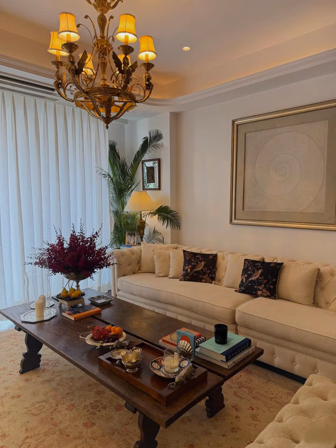 A long cream sofa rested against the wall, styled with neutral cushions. Above the sofa, hung a chandelier that added a hint of vintage charm. The rest of the house is balanced with more contemporary elements. (Image: Instagram)