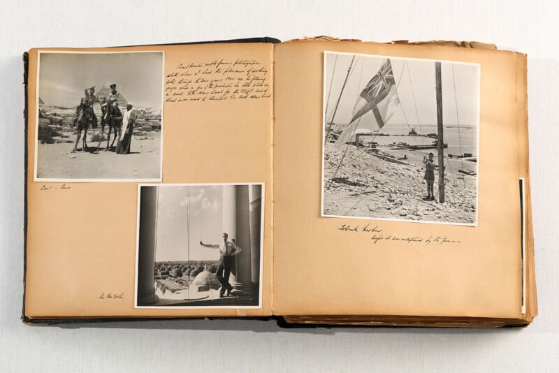 An open vintage photo album with handwritten notes, showing three black-and-white photos: two people on camels, a man addressing a crowd, and a man standing near a flagpole with a large flag.