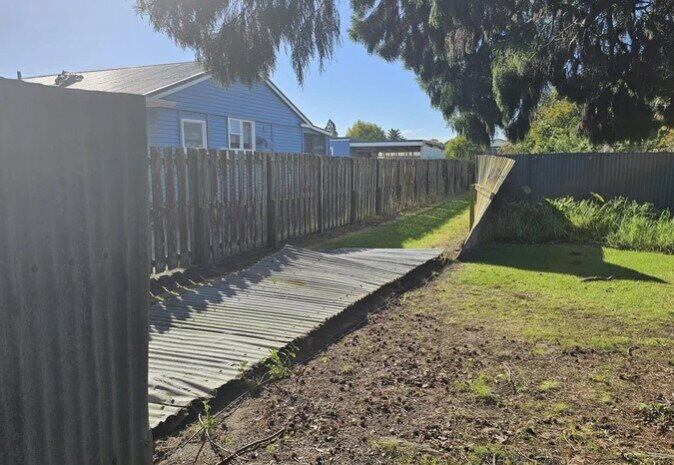 This corrugated iron fence with steel reinforced concrete posts was one of the fences in Peace St to feel the force of the tornado. Photo / Whakatāne Beacon