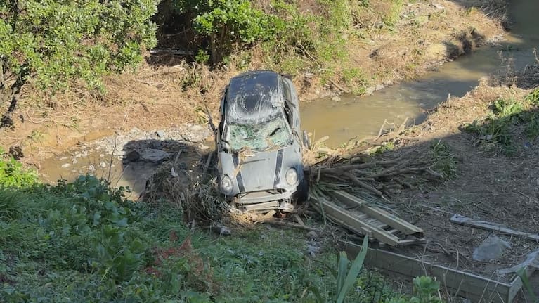 A car, washed away by floodwaters, sits at the base of the Ōwhiro Stream.
