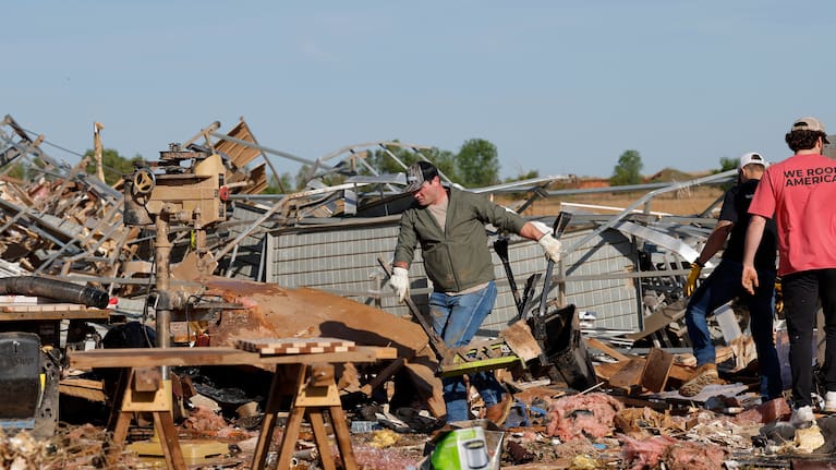A man clears debris at a commercial woodworking shop in Enid.