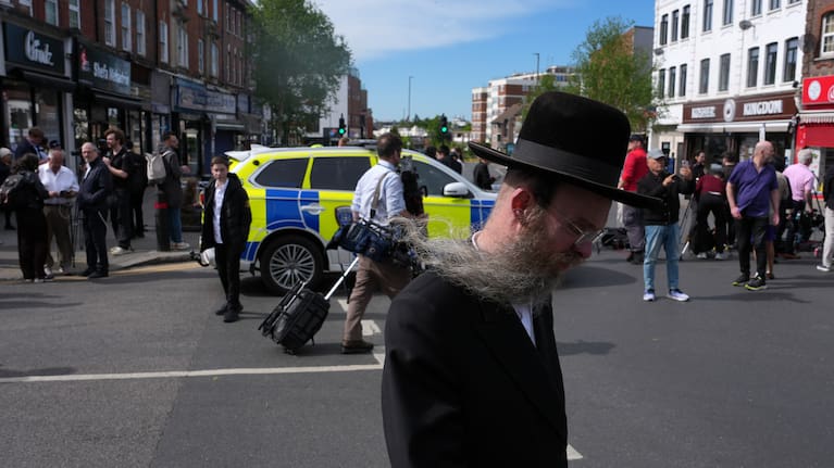 A man walks past a blocked road after two people were stabbed in Golders Green neighbourhood, that has a large Jewish community, in London.