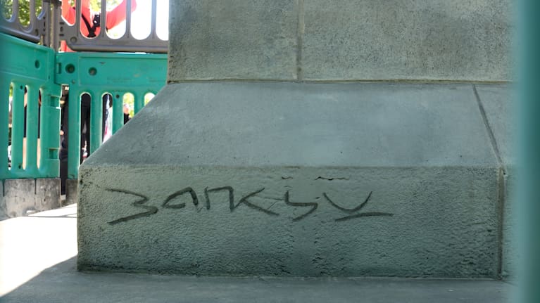 A statue of a man holding a flag which covers his face, left, and signed 'Banksy, has appeared in Waterloo Place in London.