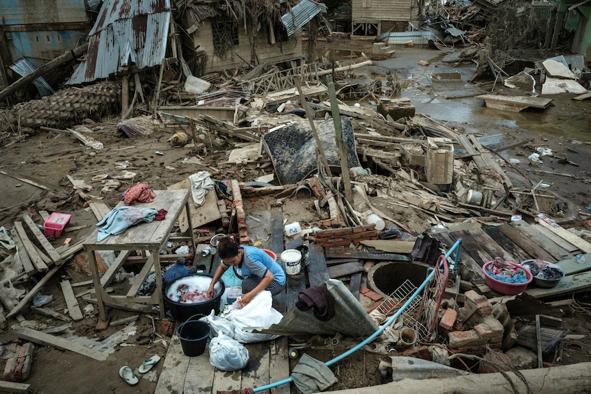A woman washes clothes in an area affected by flash floods.
