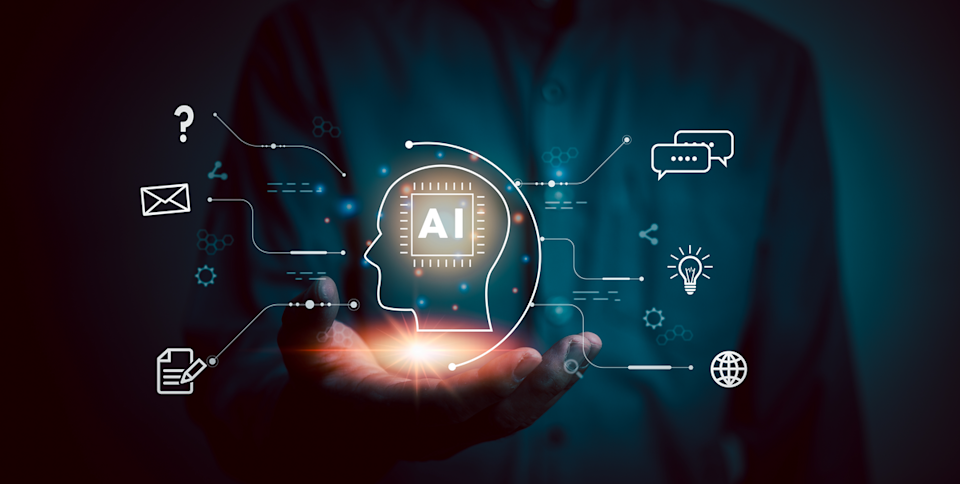 A glowing digital head with AI written inside it floats above a human hand.