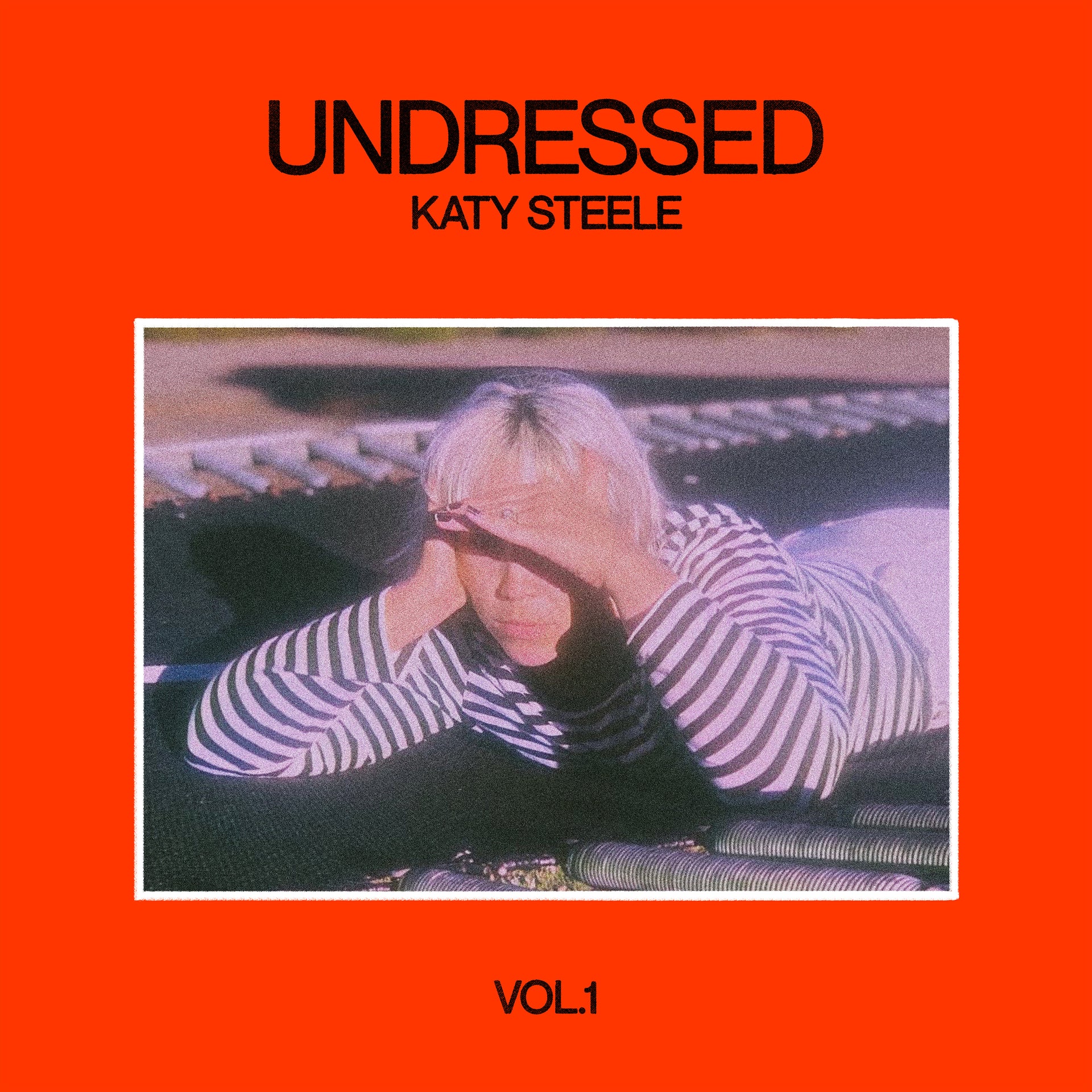 Album artwork for Katy Steele’s Undressed Vol. 1 showing an orange background with a person lying on a keyboard in a striped top
