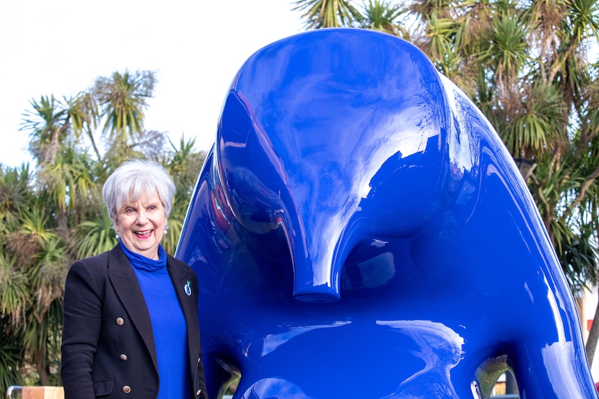 A blue sculpture with a woman next to it.
