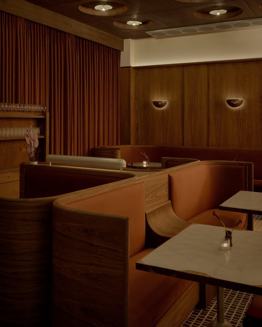 Custom banquettes featuring curved walnut backs and russet-hued velvet cushions