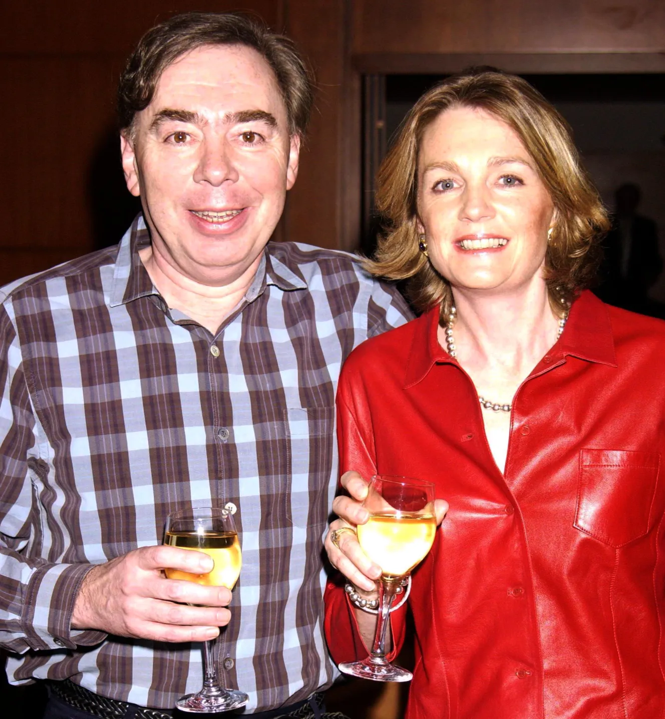Andrew Lloyd Webber and his wife Madeline, smiling and holding wine glasses.