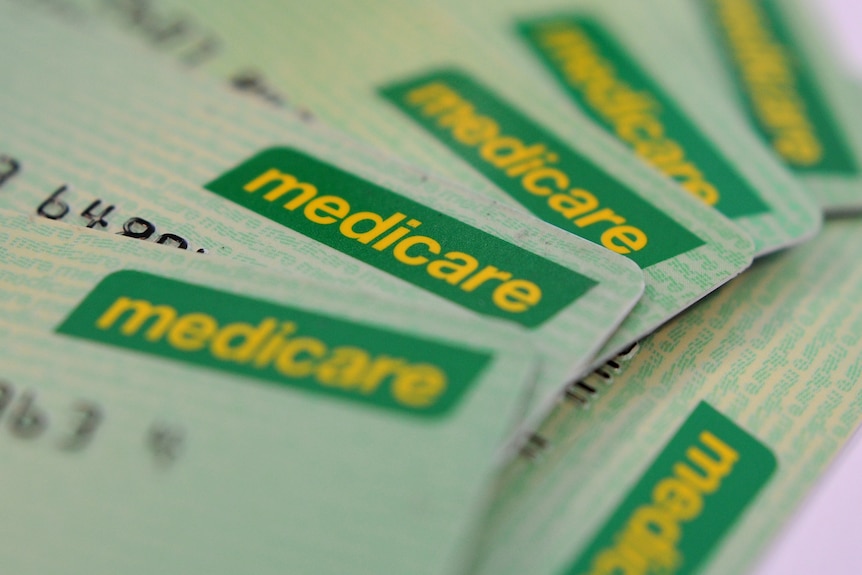 A pile of five green and yellow Medicare cards spread in a half-semi-circle