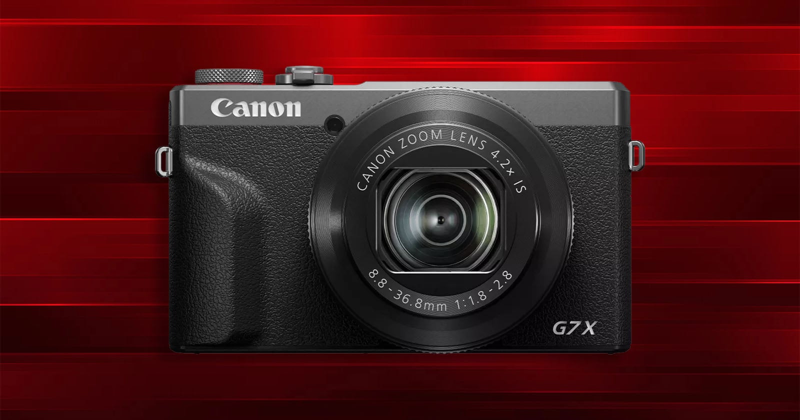 A Canon G7X digital camera with a zoom lens is displayed against a red, striped background.
