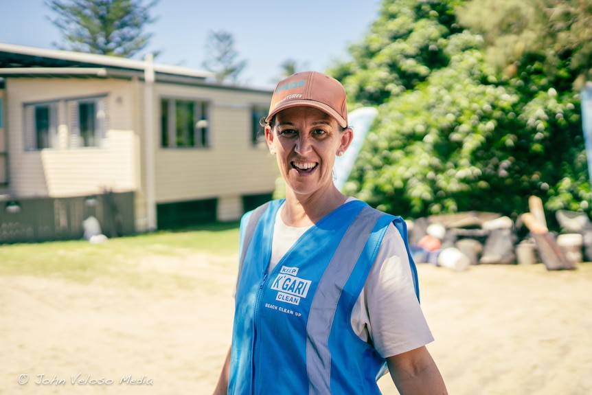 A woman wearing a blue vest and a cap smiling