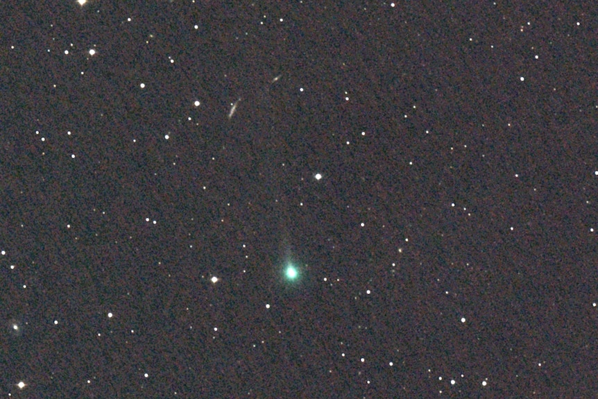 Black starfield with a faint green comet visible in the centre.