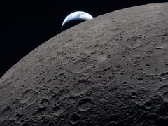 The lunar surface fills the frame in sharp detail, as seen during the Artemis II lunar flyby, while a distant Earth sets in the background.