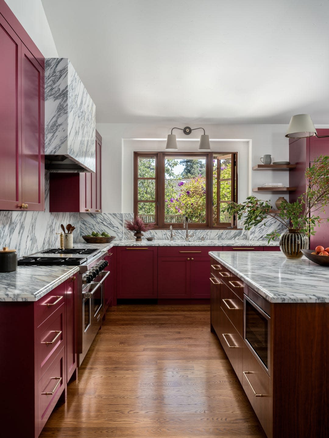 Modern kitchen featuring marbled countertops and burgundy cabinetry.