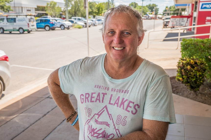 A man with grey hair wearing a t-shirt standing in a Mount Isa street.